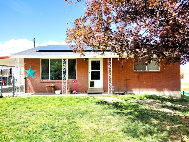 view of front of home featuring roof mounted solar panels, brick siding, and an attached carport