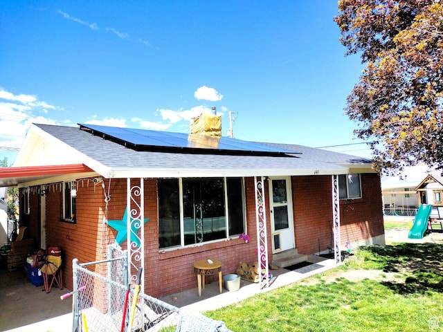 view of front of house featuring entry steps, solar panels, a chimney, and a shingled roof