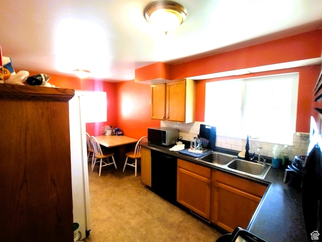 kitchen featuring dishwasher, a sink, dark countertops, and tasteful backsplash