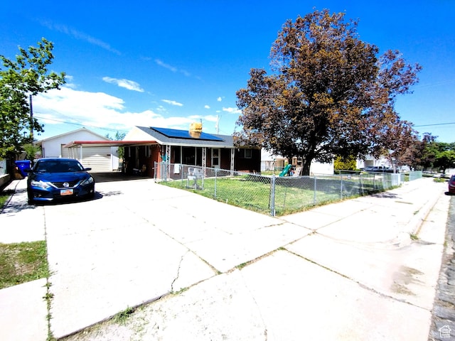 ranch-style house with concrete driveway, solar panels, and a carport