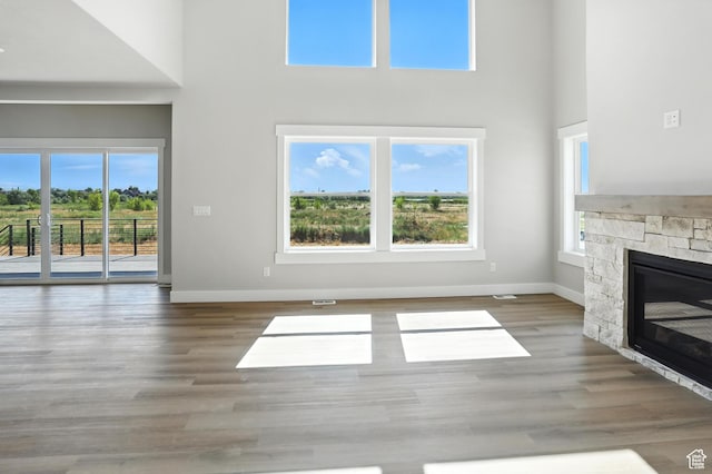 1734 N 4100 W, Plain City, UT 84404 - unfurnished living room featuring a towering ceiling, plenty of natural light, a stone fireplace, and wood finished floors