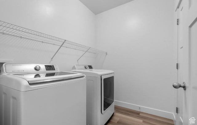 laundry room with independent washer and dryer, wood finished floors, and baseboards