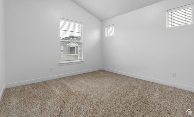 carpeted spare room with lofted ceiling and baseboards