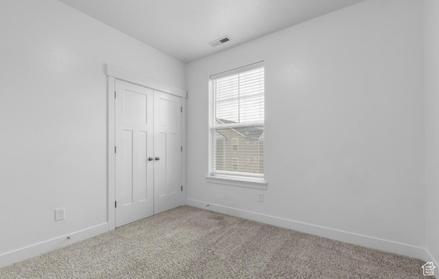 unfurnished bedroom featuring carpet flooring, baseboards, and a closet