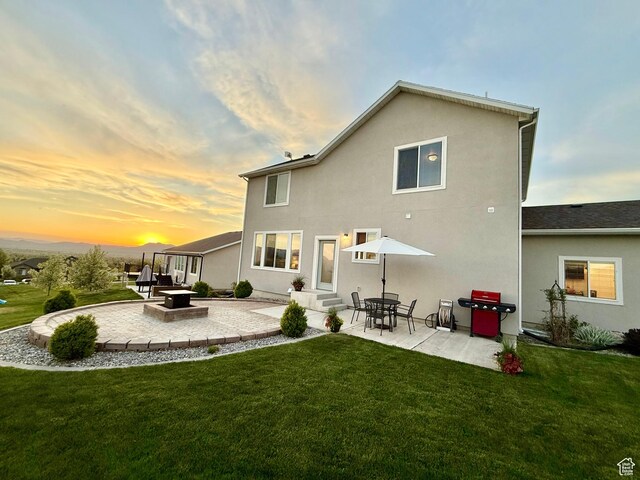 back of property at dusk featuring a patio area, a lawn, entry steps, and stucco siding