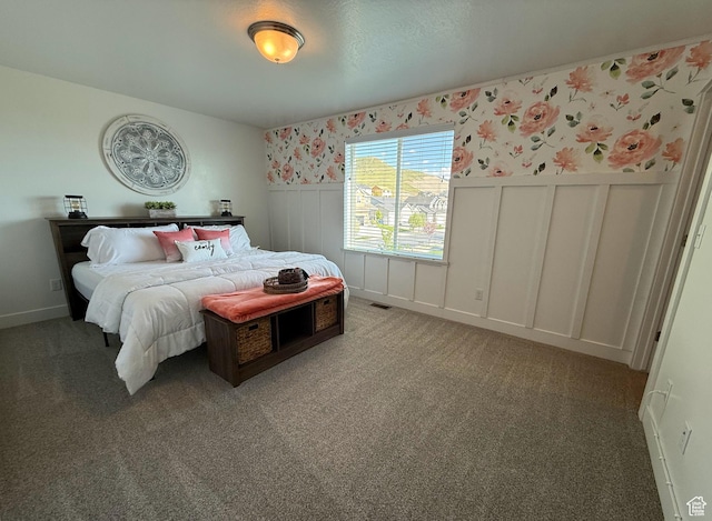 carpeted bedroom featuring wallpapered walls, wainscoting, and a decorative wall