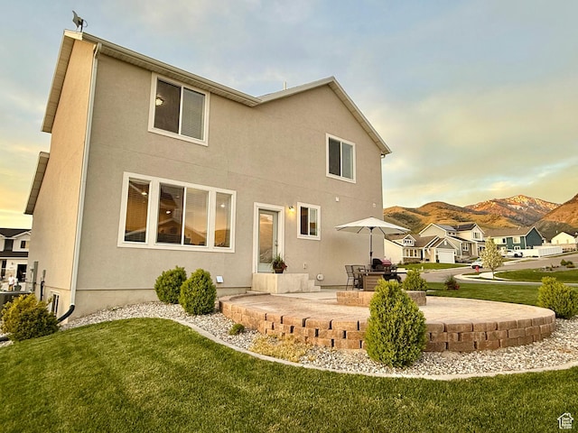 rear view of property with a patio area, a yard, stucco siding, and a mountain view