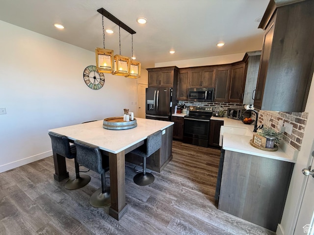 kitchen with black appliances, dark wood finished floors, light countertops, tasteful backsplash, and dark brown cabinetry