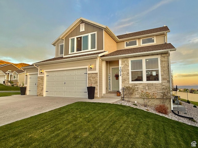 view of front facade featuring stone siding, a yard, an attached garage, concrete driveway, and board and batten siding