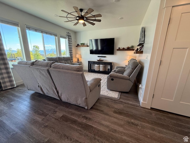 living area with dark wood-style floors, baseboards, and ceiling fan