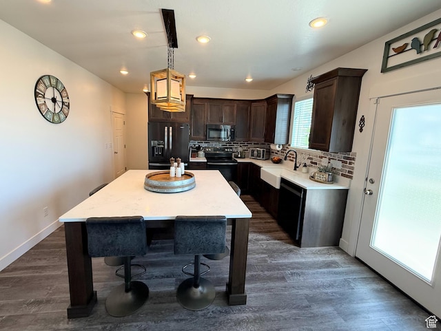 kitchen with black appliances, a sink, dark brown cabinetry, light countertops, and tasteful backsplash