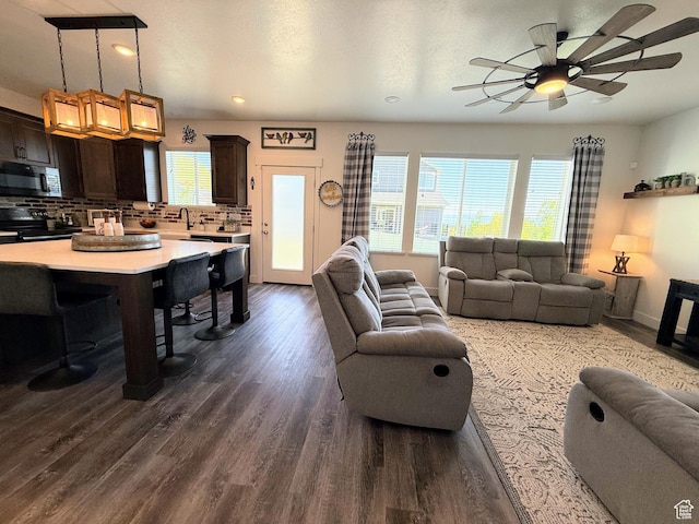 living room with healthy amount of natural light, dark wood finished floors, a ceiling fan, and recessed lighting
