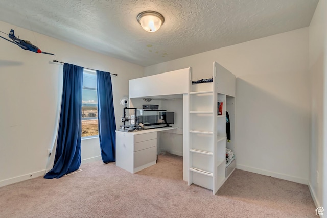 unfurnished bedroom with light colored carpet, a textured ceiling, and baseboards