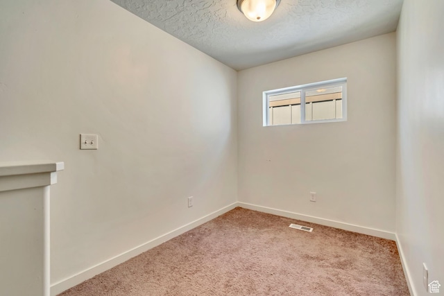 unfurnished room featuring baseboards, carpet floors, and a textured ceiling
