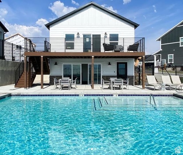 back of property with a balcony, stairway, fence, and a patio area