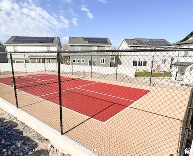 view of basketball court with a tennis court and fence