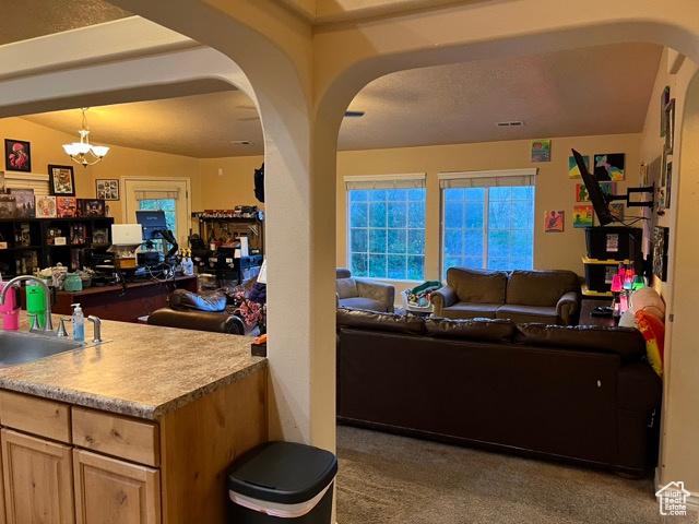 1195 W Dallin Dr N Unit R301, Pleasant Grove, UT 84062 - carpeted living room featuring a sink, arched walkways, and a chandelier