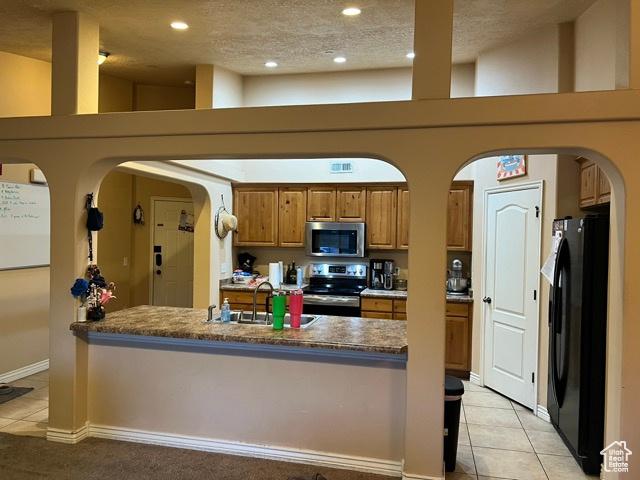 1195 W Dallin Dr N Unit R301, Pleasant Grove, UT 84062 - kitchen with stainless steel appliances, arched walkways, brown cabinets, light tile patterned floors, and recessed lighting