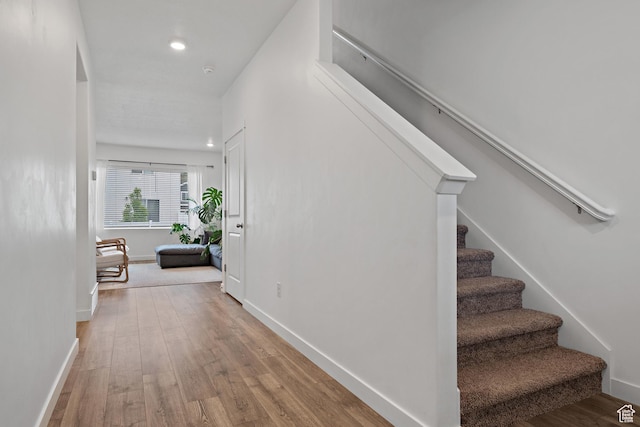 hall with stairs, wood finished floors, baseboards, and recessed lighting