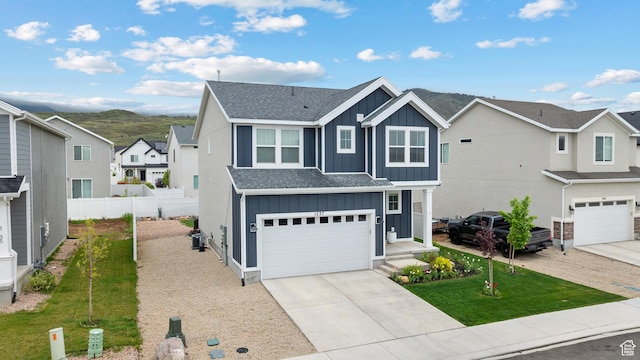 traditional home with board and batten siding, an attached garage, roof with shingles, and a residential view