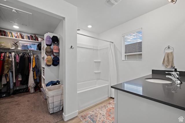 full bathroom with a walk in closet, wood finished floors, vanity, shower / bath combo with shower curtain, and recessed lighting