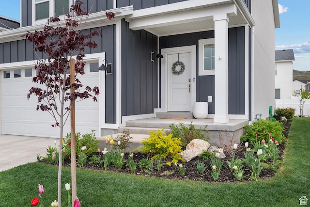 doorway to property featuring board and batten siding, driveway, and a lawn