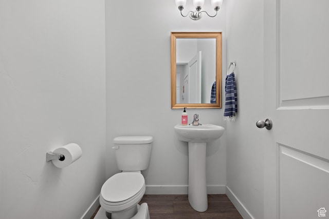 half bath featuring baseboards, toilet, and wood finished floors