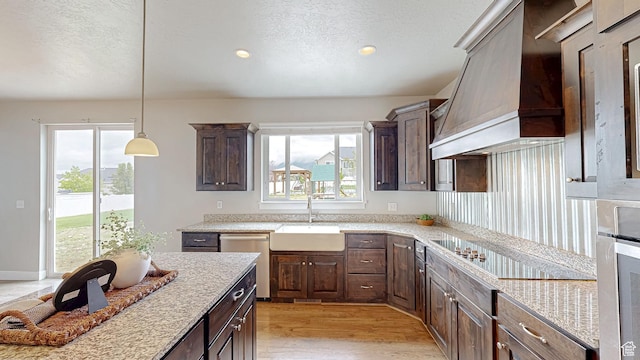 kitchen featuring custom range hood, a sink, stainless steel dishwasher, a textured ceiling, and dark brown cabinetry