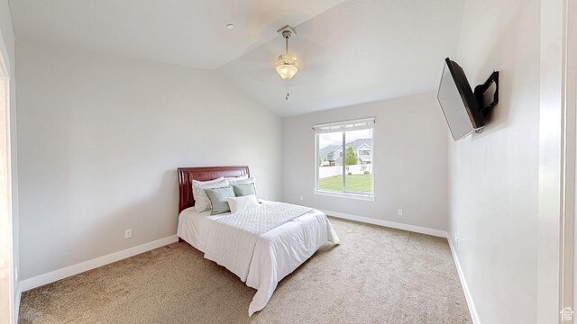 bedroom with light carpet, lofted ceiling, and baseboards