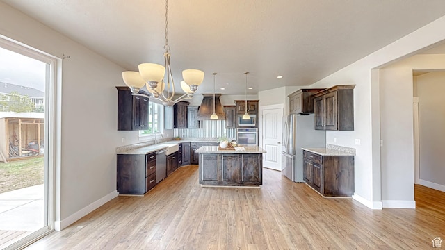 kitchen featuring stainless steel appliances, dark brown cabinetry, light wood finished floors, a kitchen island, and a chandelier