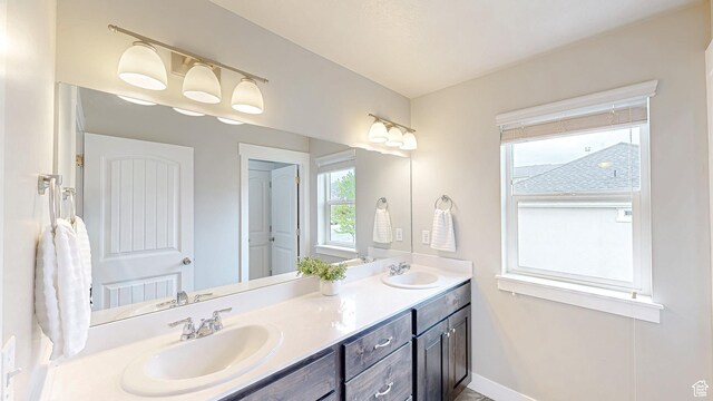 bathroom with double vanity and baseboards