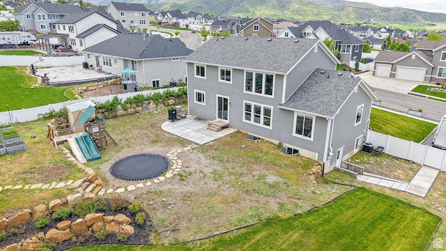 rear view of property with a residential view, roof with shingles, a patio area, and a playground