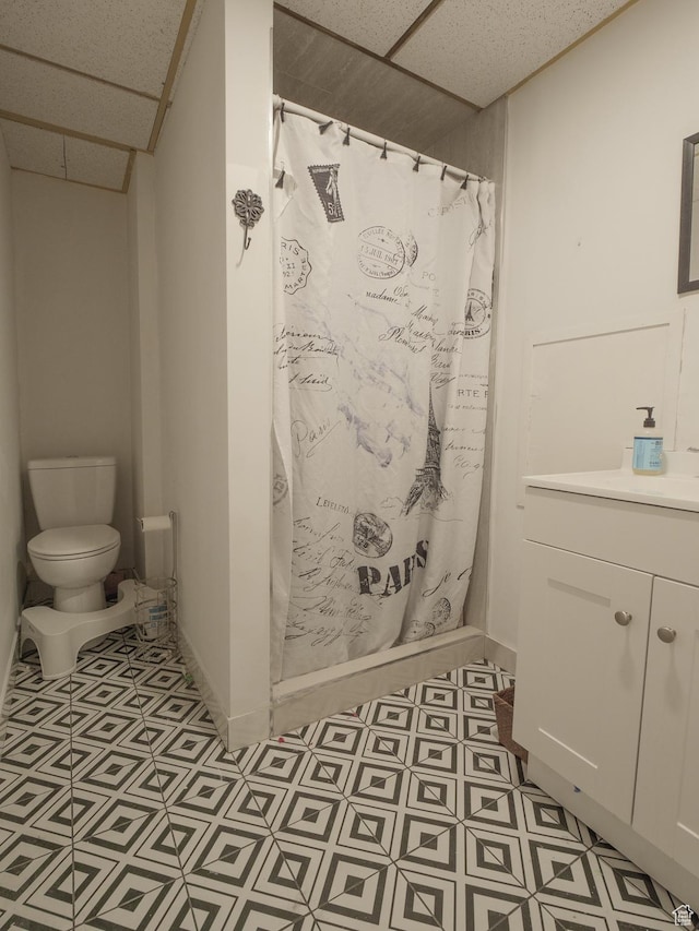 full bath with a drop ceiling, toilet, curtained shower, a sink, and tile patterned floors