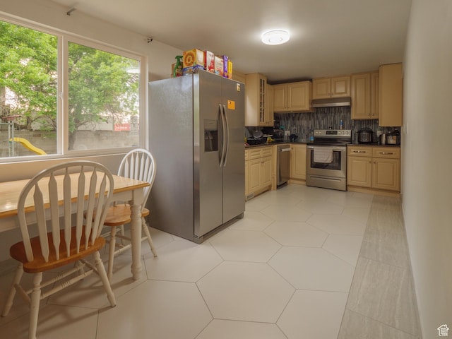 kitchen featuring appliances with stainless steel finishes, under cabinet range hood, dark countertops, decorative backsplash, and glass insert cabinets