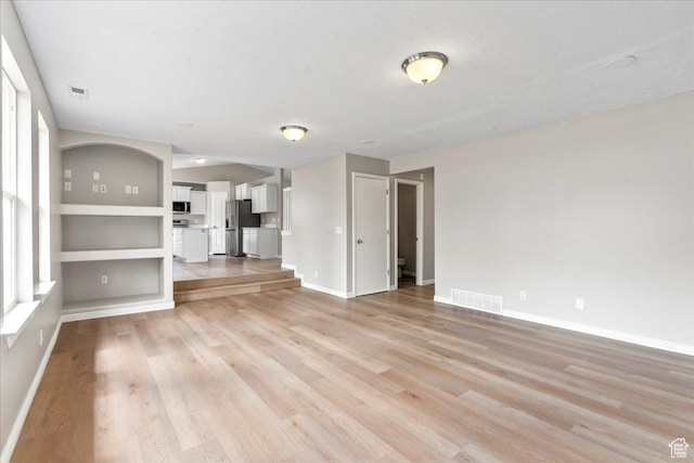 unfurnished living room featuring light wood-style flooring and baseboards