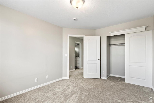 unfurnished bedroom featuring carpet, baseboards, a closet, and a textured ceiling