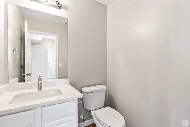 half bathroom featuring toilet, vanity, and baseboards