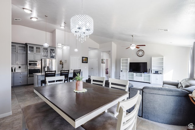 dining room with ceiling fan, high vaulted ceiling, and a chandelier