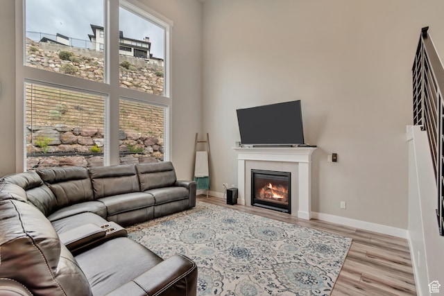 5402 N Meadow Lark Ln, Lehi, UT 84043 - living area with light wood-style floors, a glass covered fireplace, a towering ceiling, and baseboards