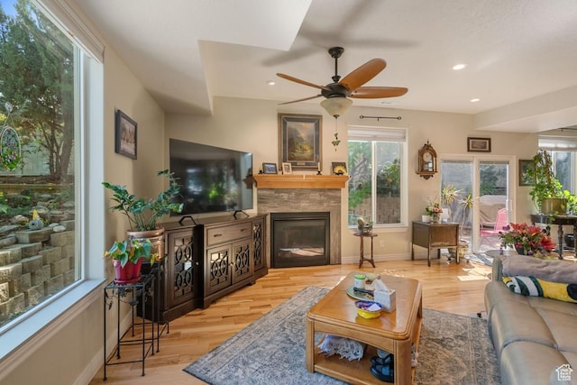 living room with a glass covered fireplace, plenty of natural light, a ceiling fan, wood finished floors, and recessed lighting