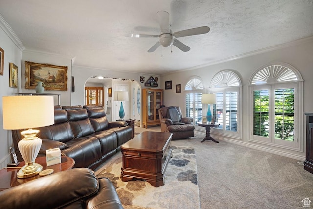 carpeted living room with arched walkways, ceiling fan, and ornamental molding