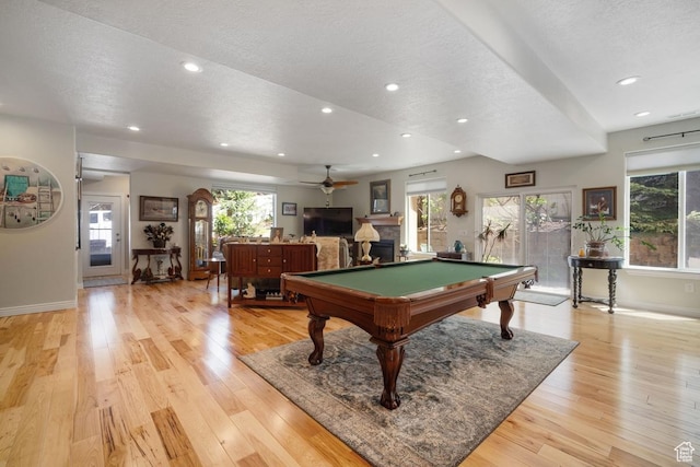 game room featuring a textured ceiling, baseboards, light wood-style flooring, a ceiling fan, and pool table