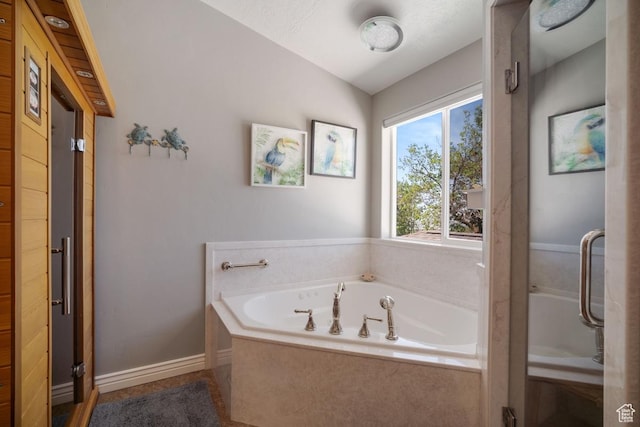 full bathroom with a bath, lofted ceiling, and baseboards