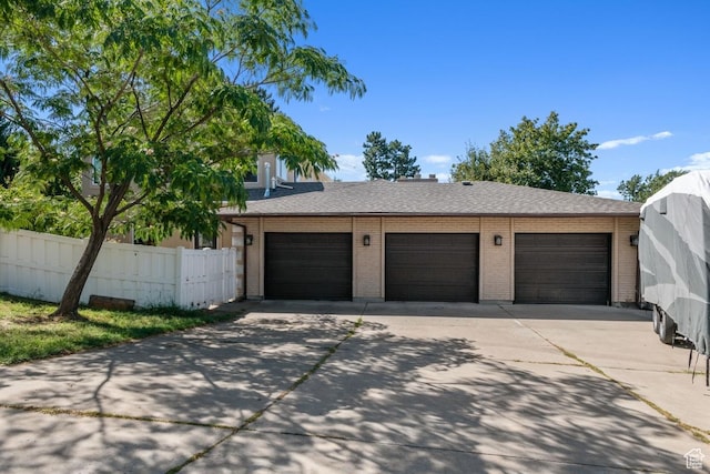 garage featuring fence and concrete driveway