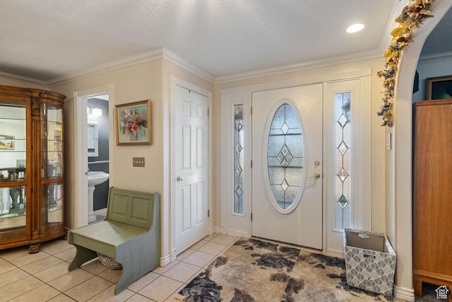 foyer featuring crown molding, light tile patterned floors, arched walkways, and baseboards