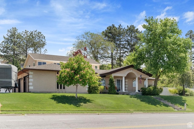 view of front of property with brick siding, a front yard, and an attached garage