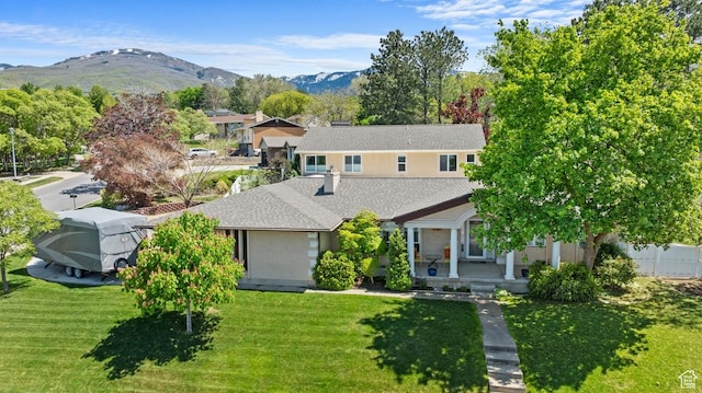 view of front of house featuring a front lawn, a porch, a mountain view, and a shingled roof