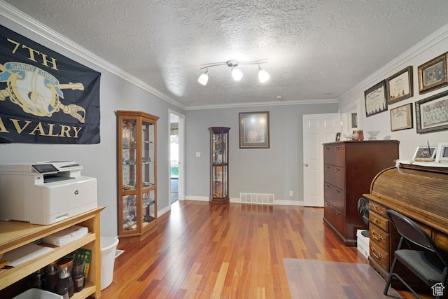 office area featuring wood finished floors, a textured ceiling, ornamental molding, and baseboards