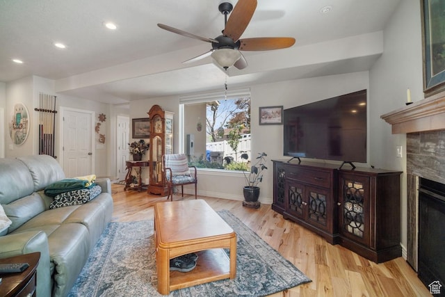 living room featuring light wood finished floors, ceiling fan, baseboards, recessed lighting, and a fireplace