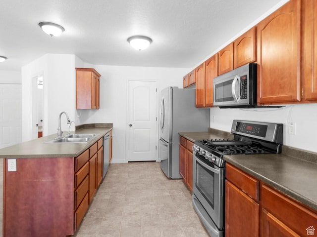 kitchen with stainless steel appliances, a sink, dark countertops, a peninsula, and brown cabinetry